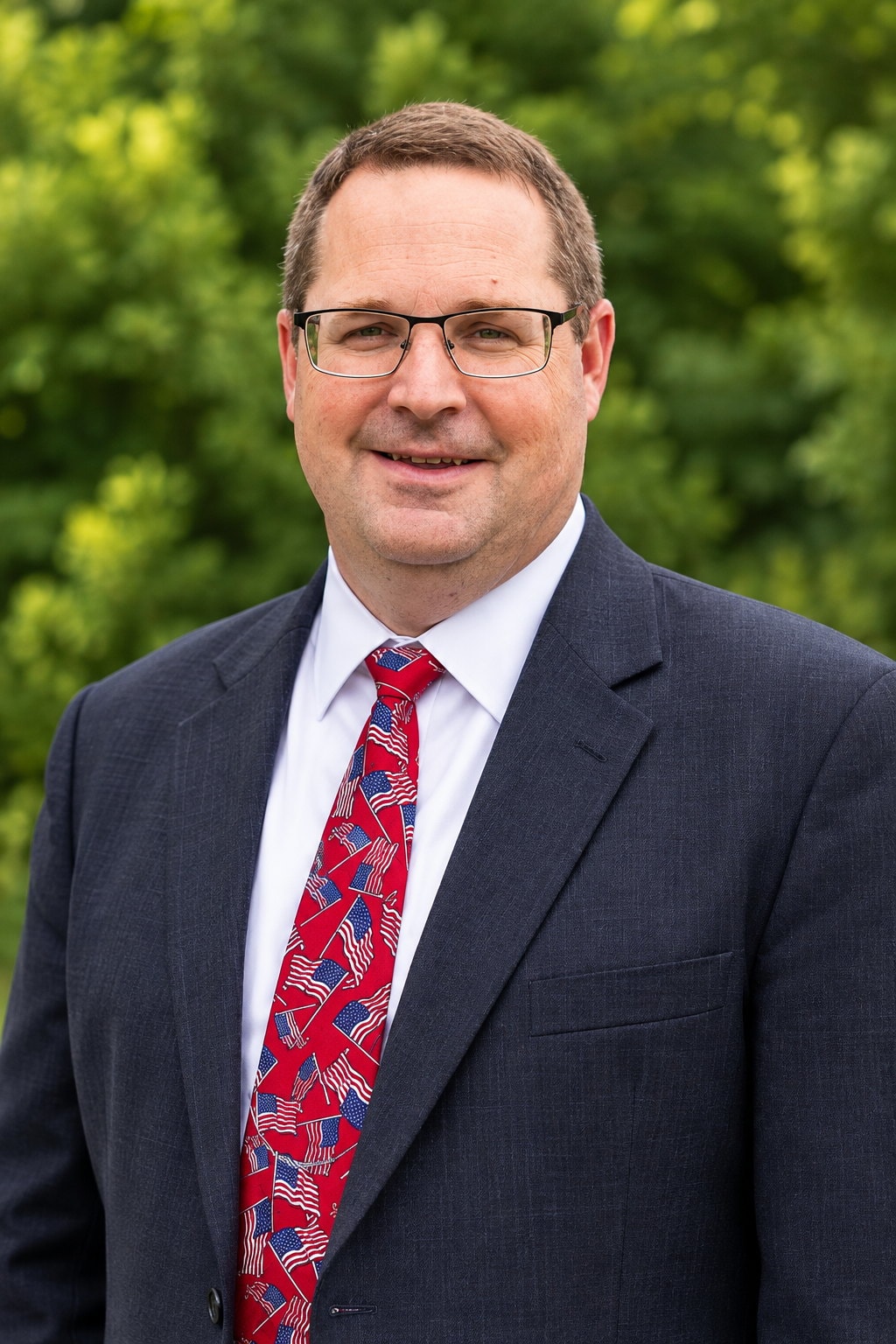 Pastor Paul Harvey of Countryside Baptist Church, standing outdoors in a dark suit and flag-patterned tie.